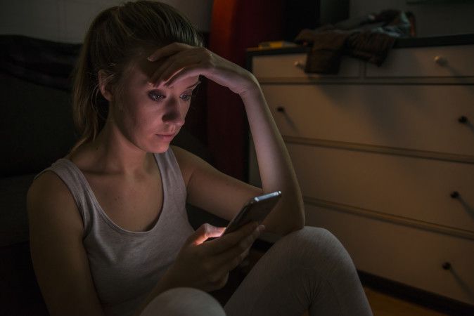 Sad and grumpy teenage girl sending message on her smart mobile