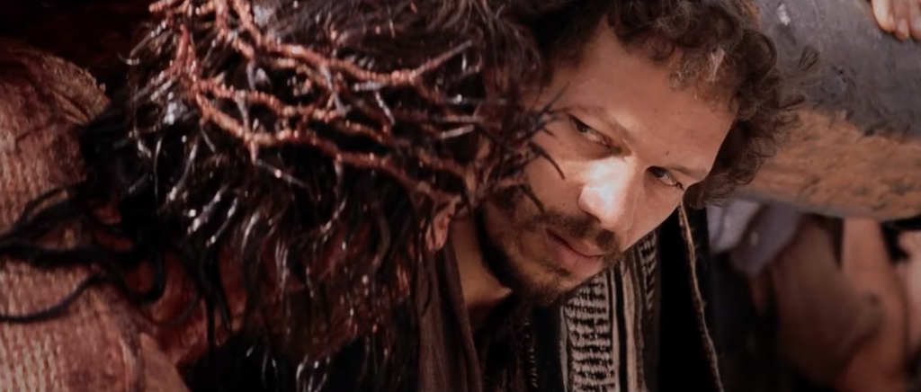 Szymon dźwiga krzyż Jezusa | Kadr z filmu "Pasja" Mela Gibsona